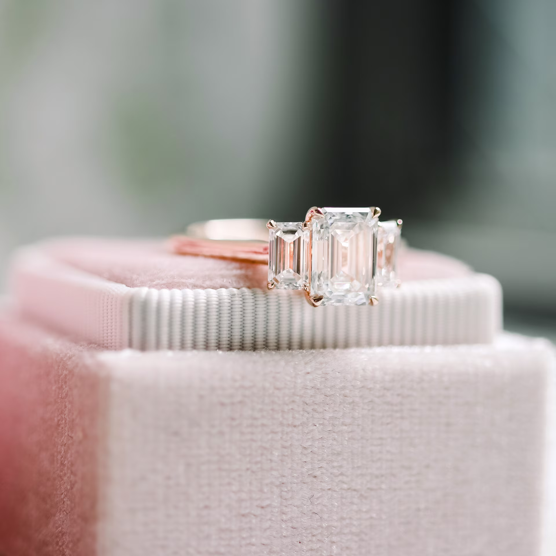 custom rose gold emerald three stone setting featuring 3ct emerald cut lab grown diamond with emerald side stones