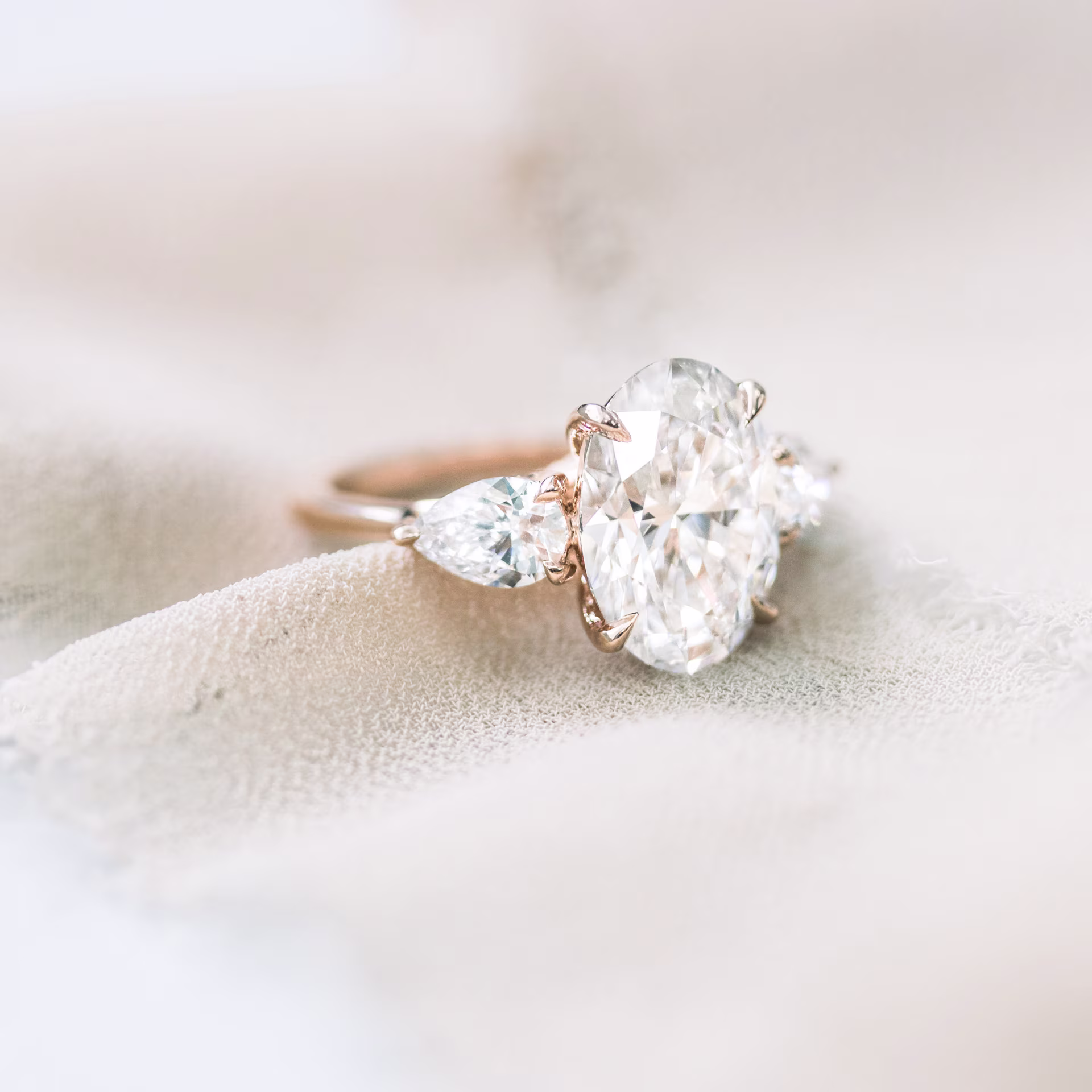 14 karat rose gold oval and pear setting featuring laboratory grown oval and pear side stones