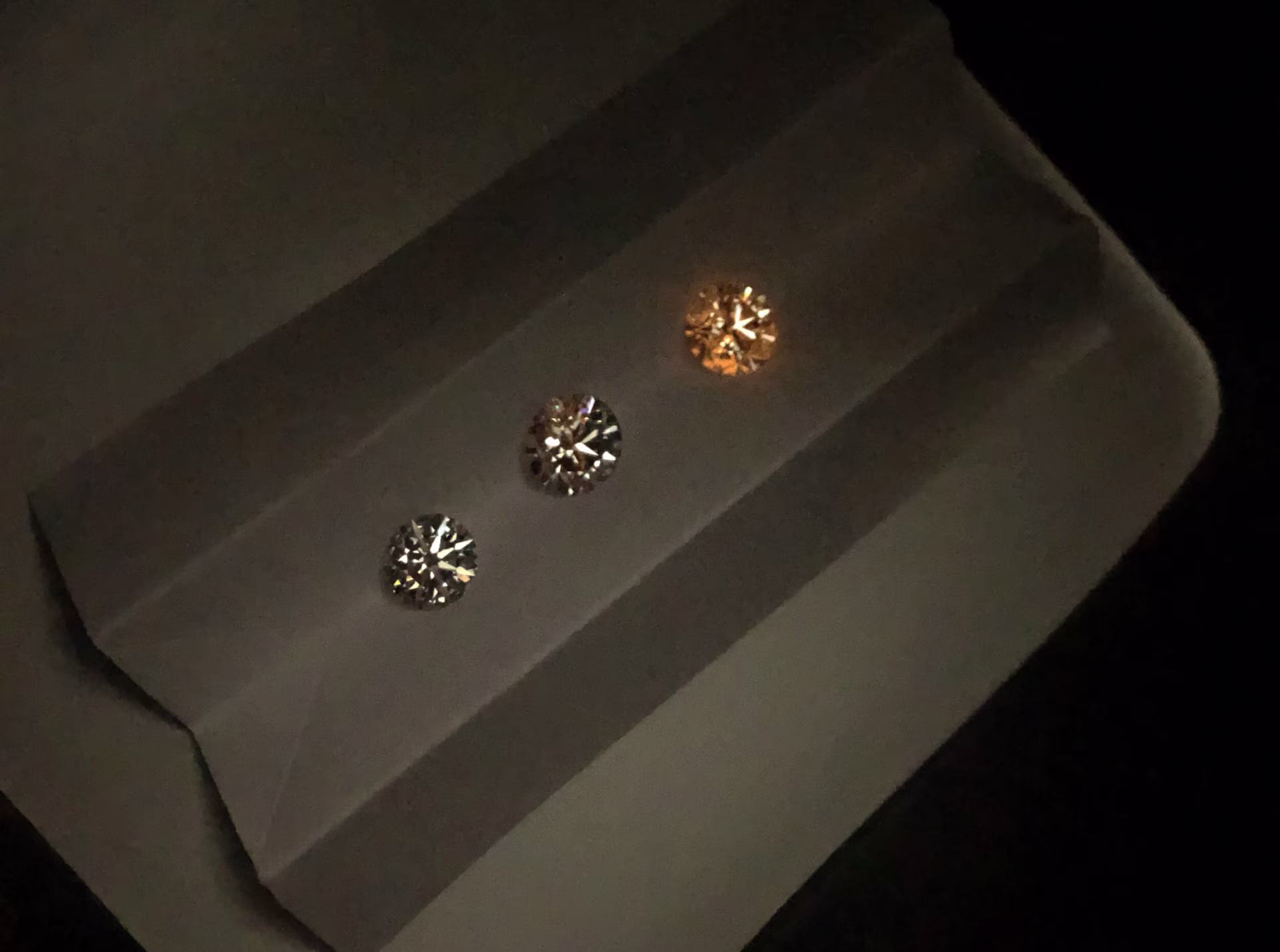 Three lab diamonds showing varying levels of phosphorescence under UV light