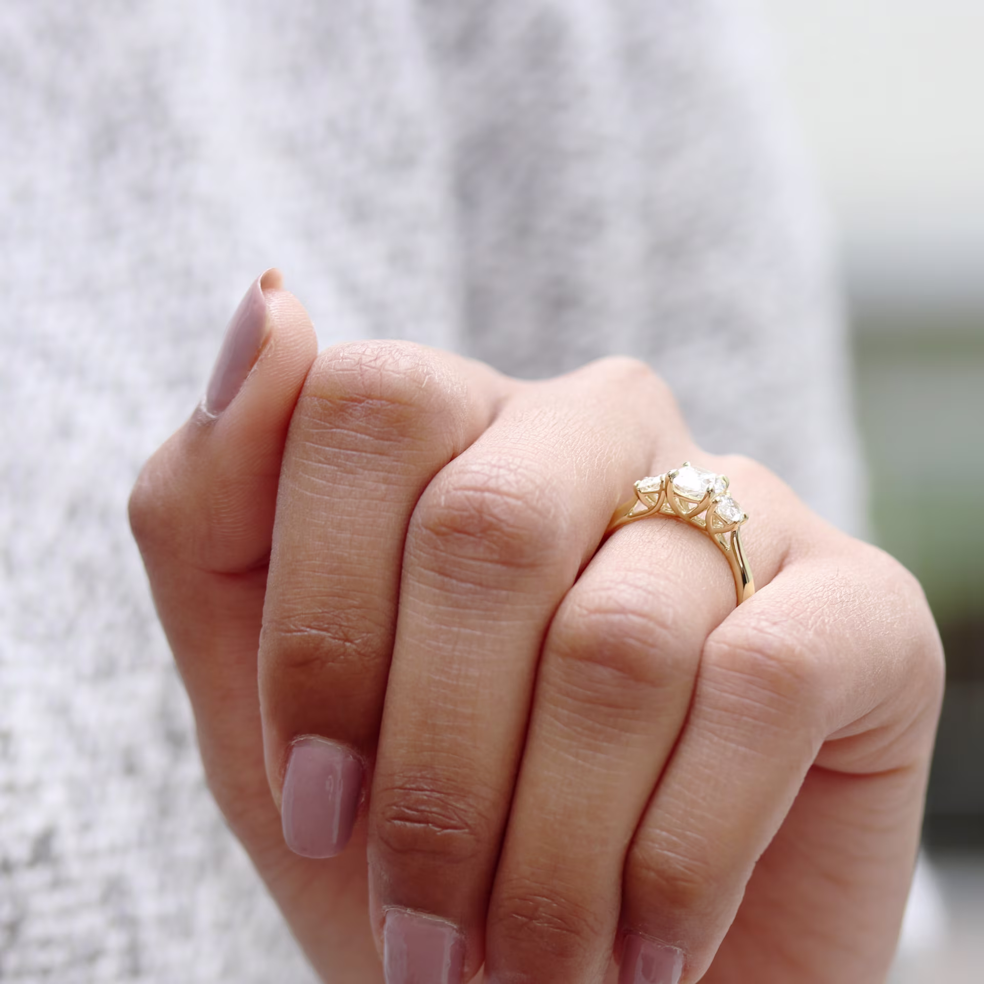 oval lab grown diamond set in a yellow gold oval three stone setting with a trellis