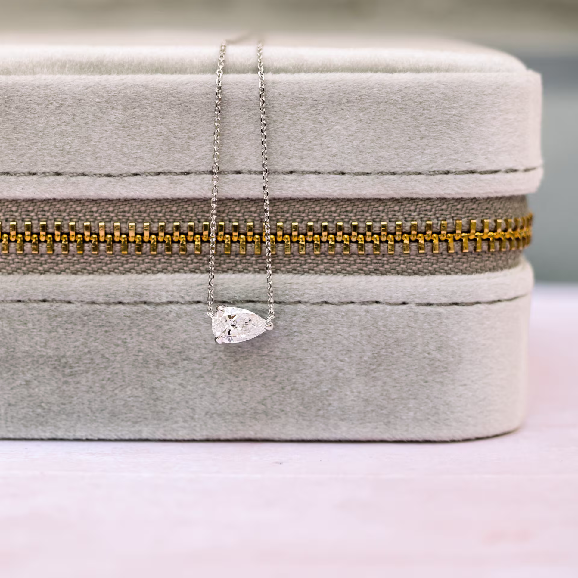 white gold floating pear pendant on gray box