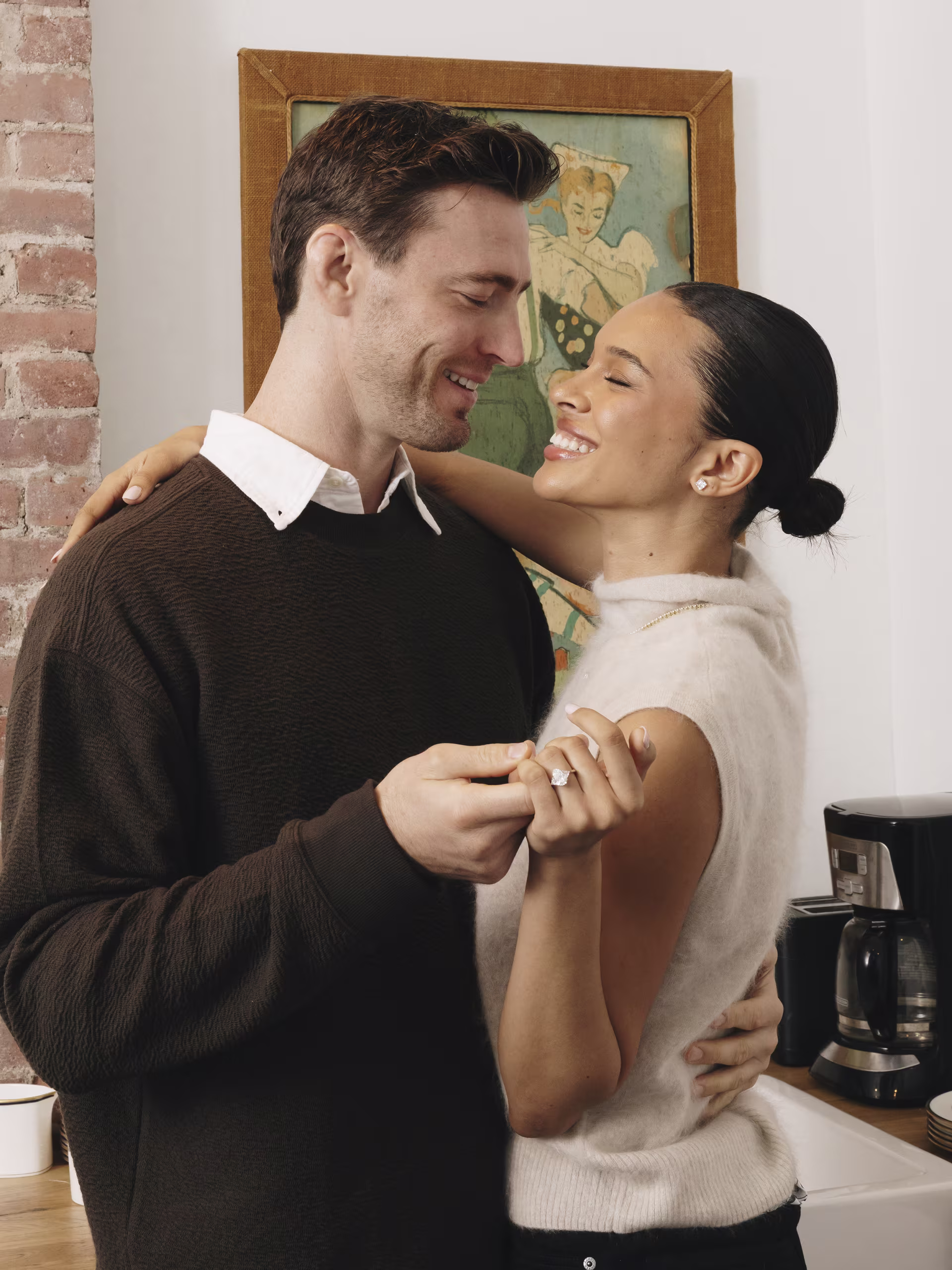 three stone pear and trillon lab diamond engagement ring on couple embracing in their kitchen