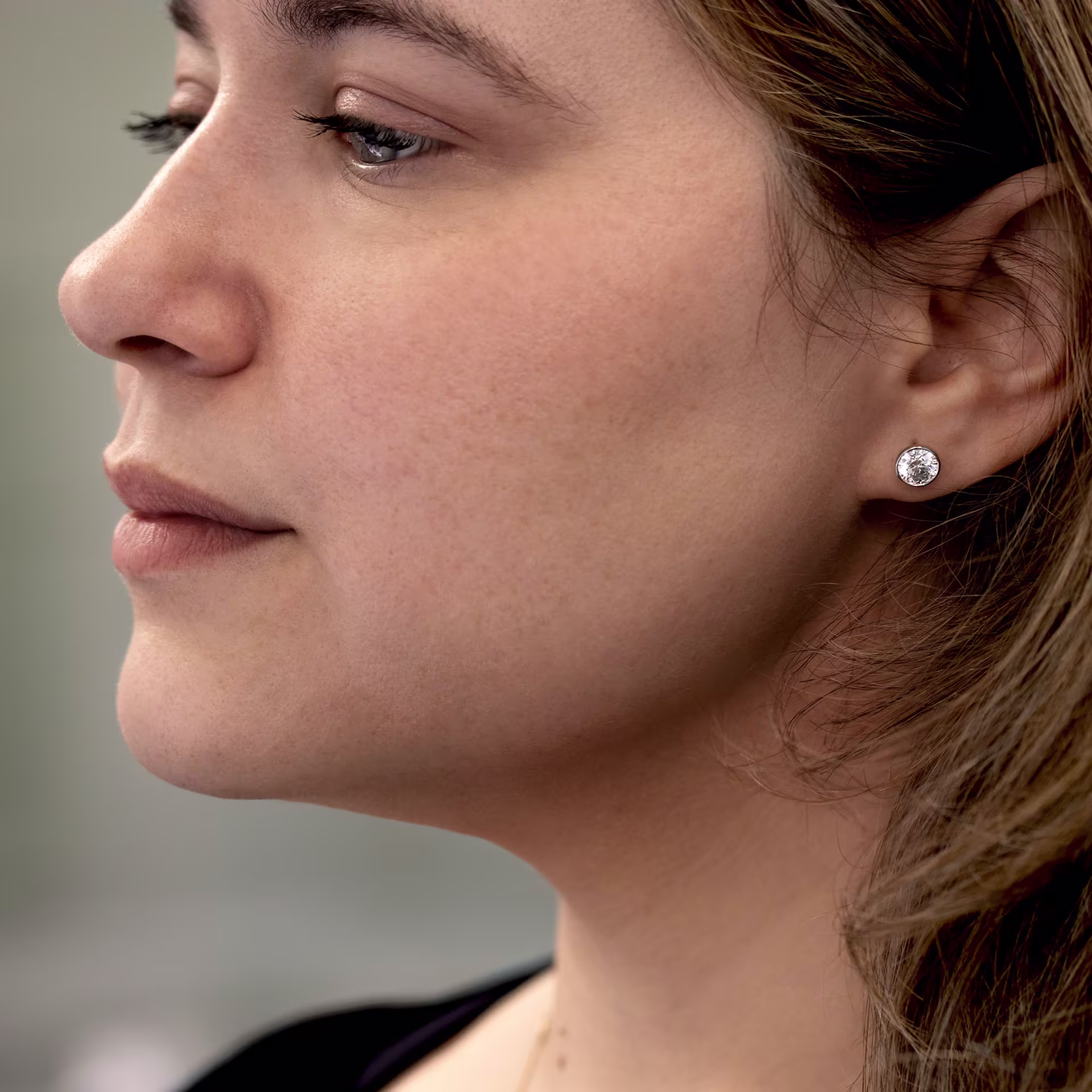 Round bezel set lab diamond stud earrings in platinum on model