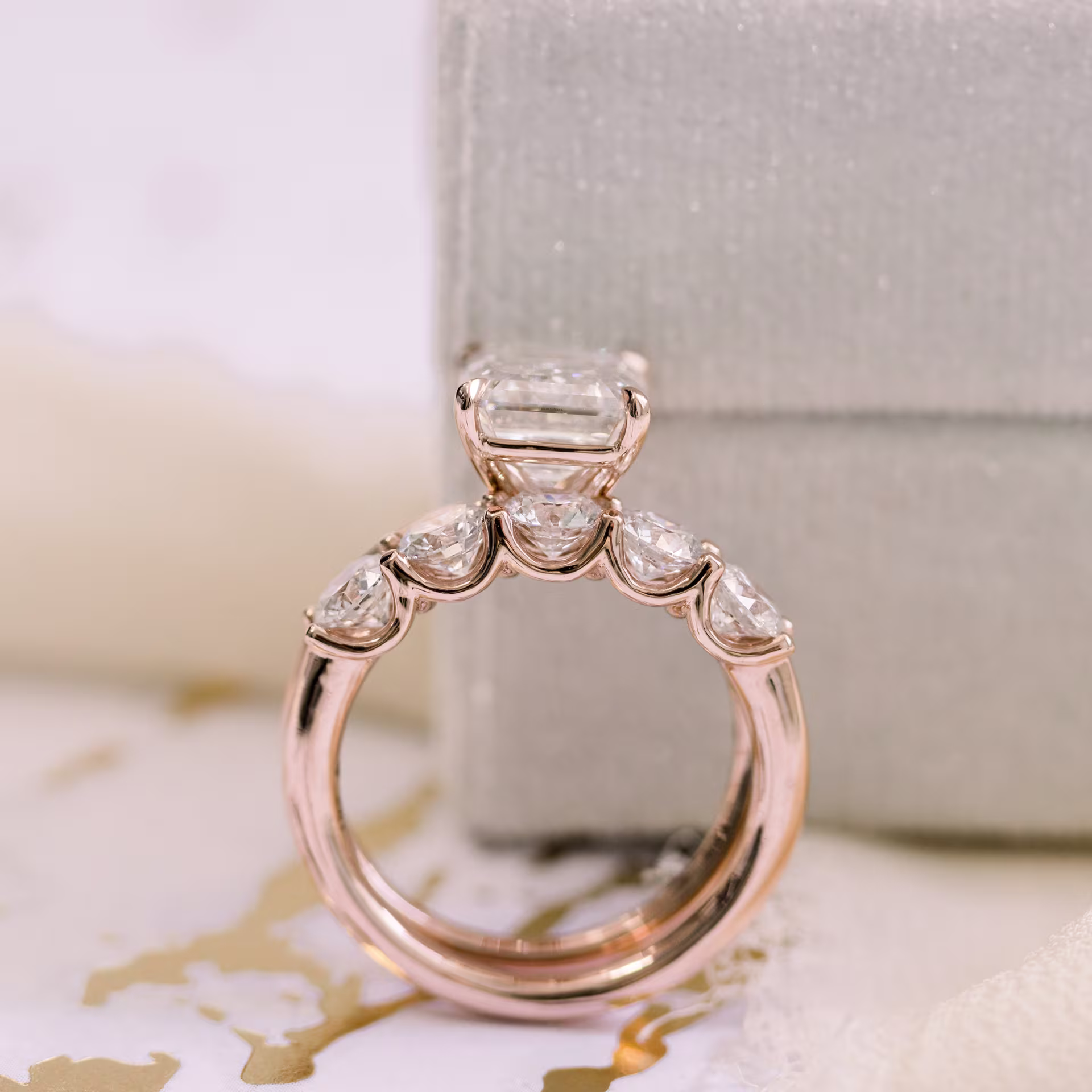 Lab diamond wedding set with 4 carat emerald cut solitaire and five stone band in rose gold profile view
