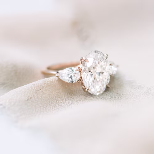 14 karat rose gold oval and pear setting featuring laboratory grown oval and pear side stones