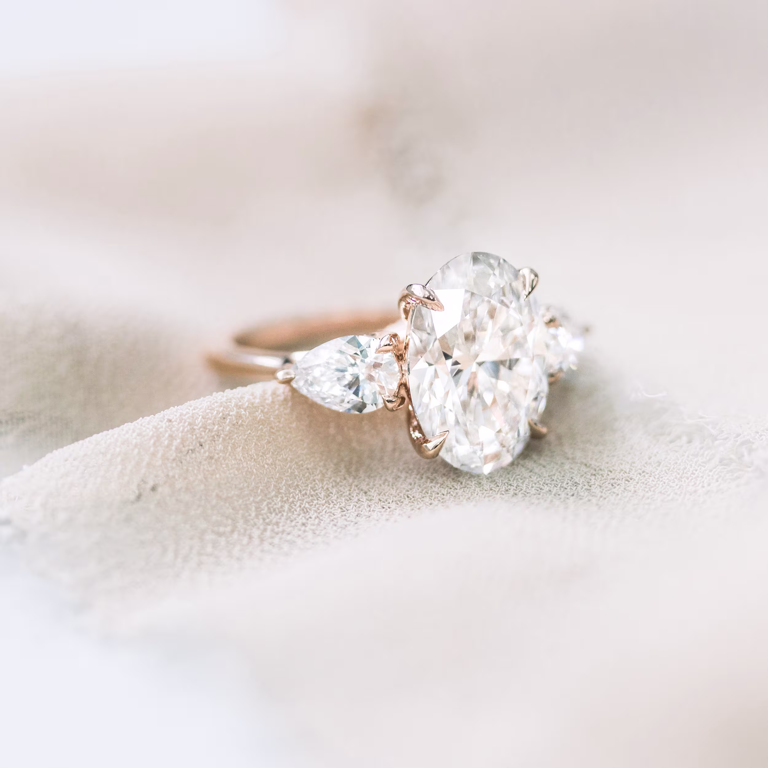 14 karat rose gold oval and pear setting featuring laboratory grown oval and pear side stones