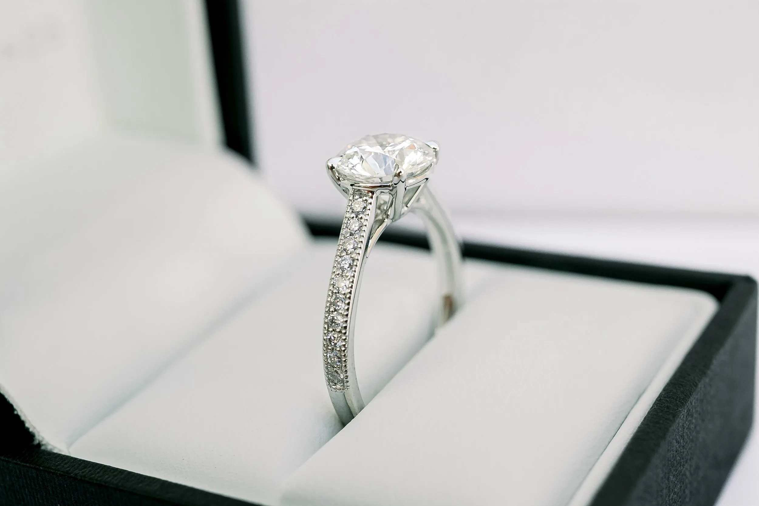 platinum 2 carat round lab diamond engagement ring with channel set diamond band and milgrain details ada diamonds design ad 074