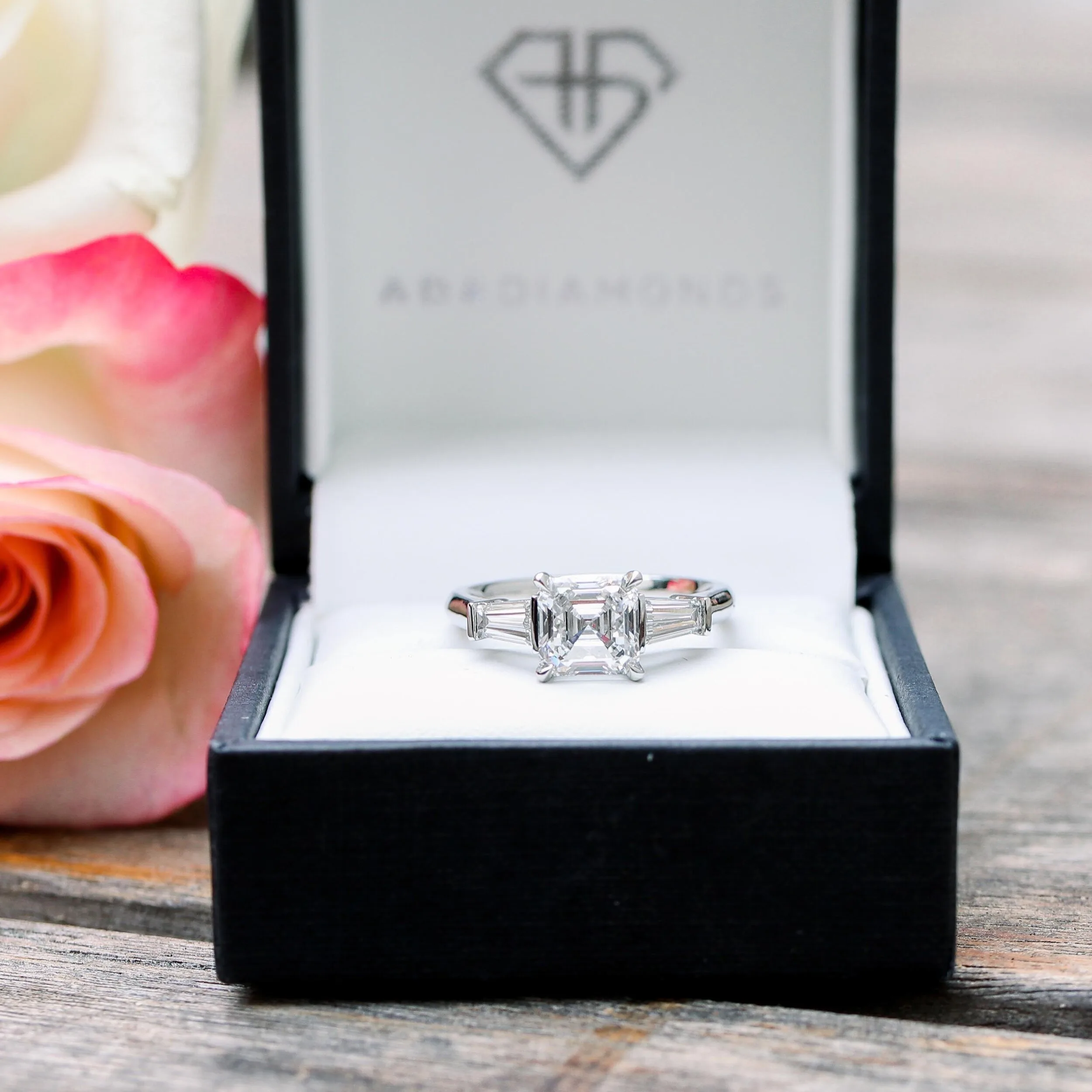 platinum three stone engagement ring featuring lab grown asscher cut diamond and tapered baguettes