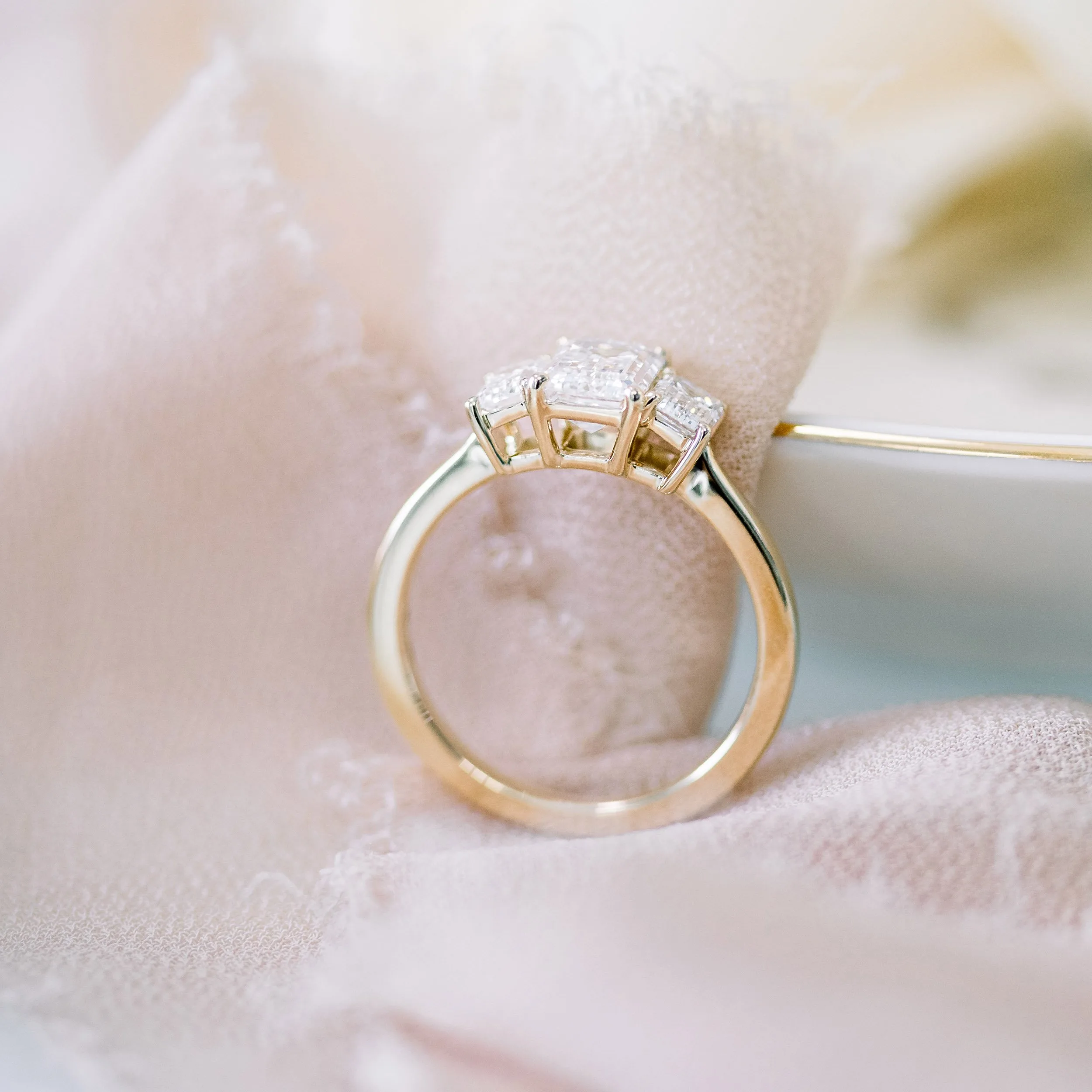 yellow gold three stone lab diamond engagement ring featuring emerald cuts